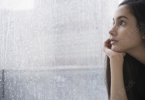 Serious Hispanic teenager looking out window
