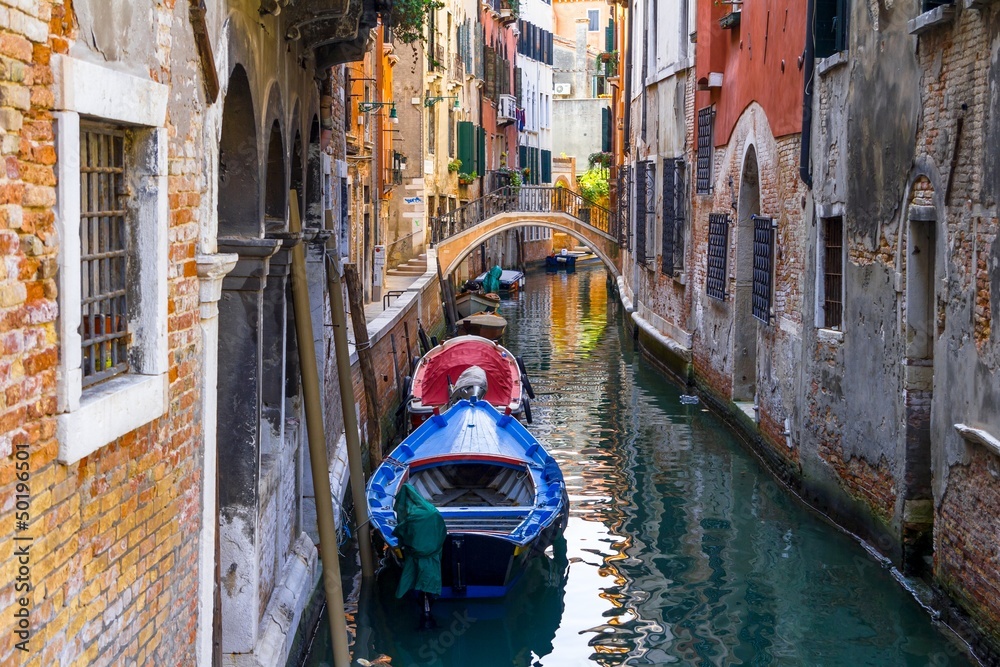 Small channel in Venice, Italy with boats parked around