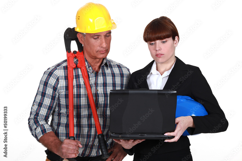 An architect and a foreman looking at a computer. An architect and a foreman looking at a computer.