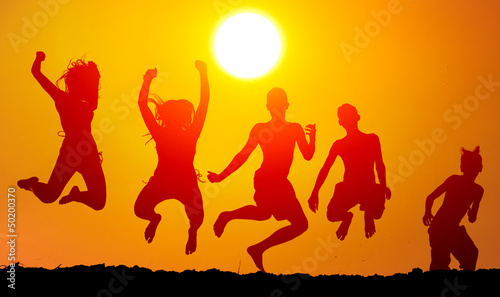 Silhouettes of happy teenagers jumping high in the air