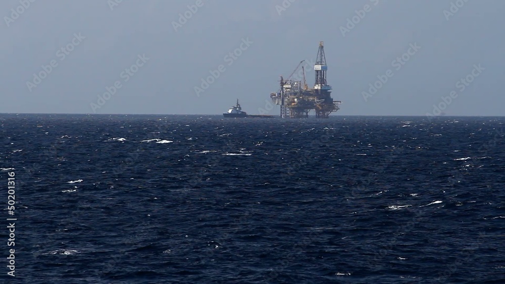 Jack up drilling rig and crew boat in the middle of the coean