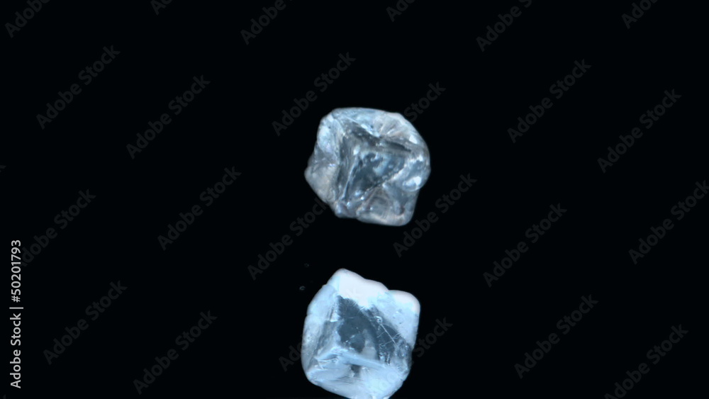 Two ice cubes falling on black background