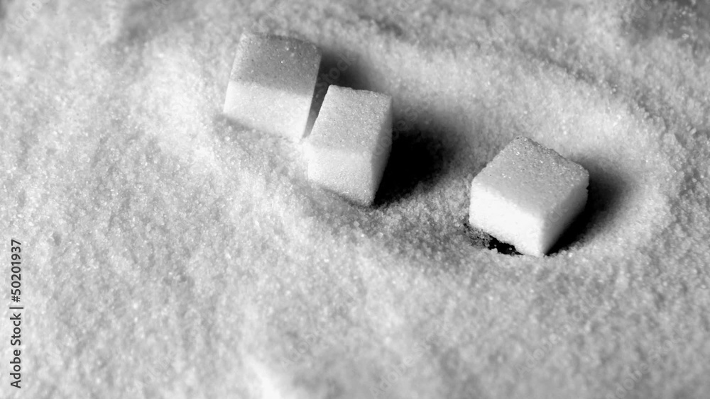 Sugar cubes falling in pile of sugar