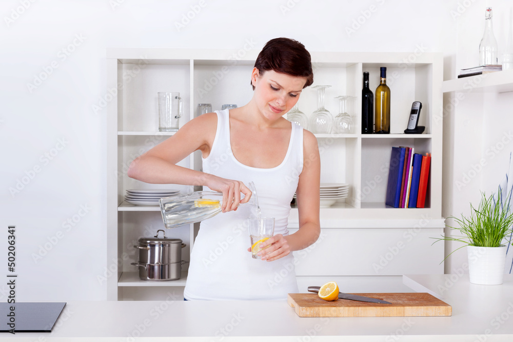 young woman preparing and drinking lemonade in her kitchen young woman preparing and drinking lemonade in her kitchen