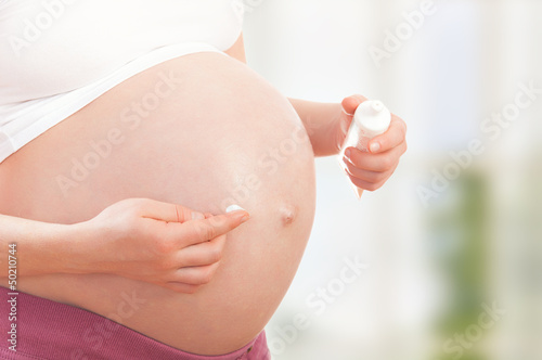 belly of pregnant woman  and moisturizing cream photo