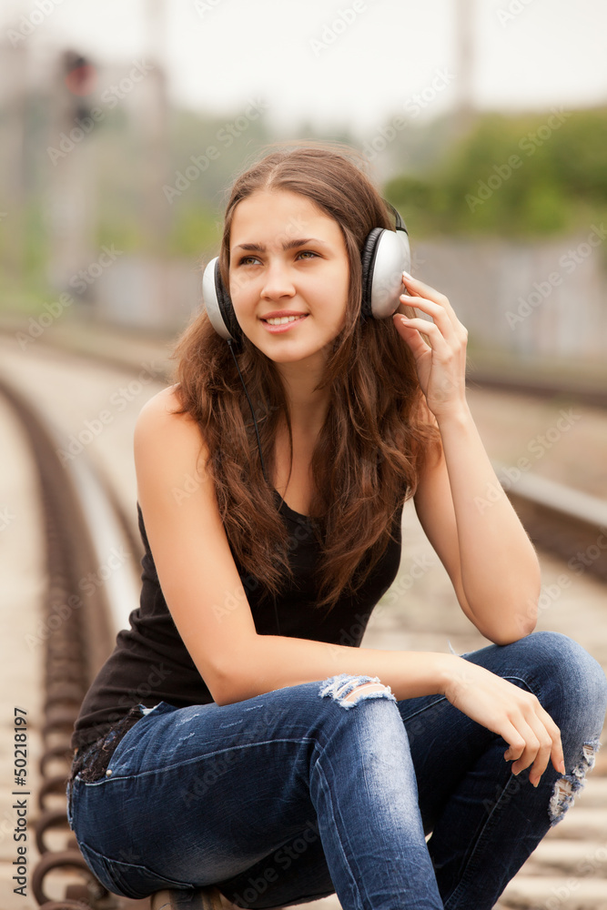Fototapeta premium Teen girl with headphones at railways.