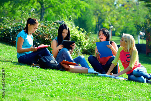 group of female friends learn on green lawn