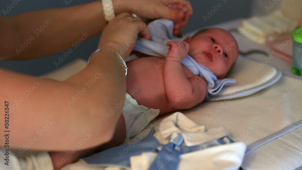Mother dressing her  baby