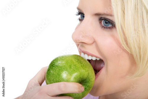 Blonde Frau beisst lachend in Apfel