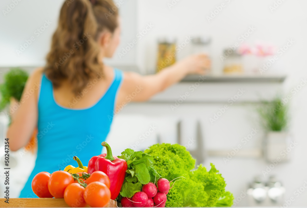 Closeup on vegetable and young housewife in background