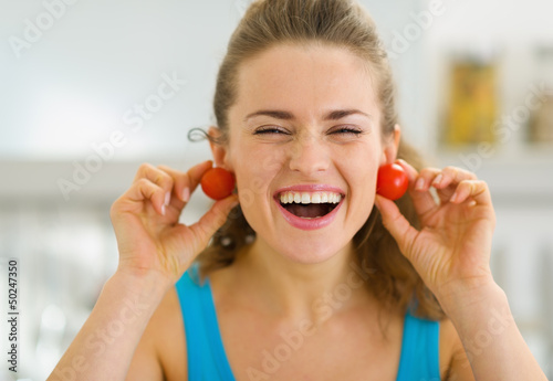 Smiling young woman using cherry tomato as earrings