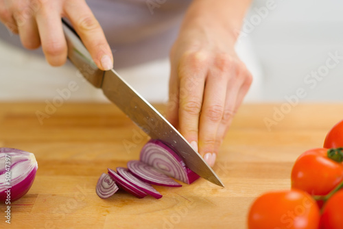 Closeup on woman cutting red onion