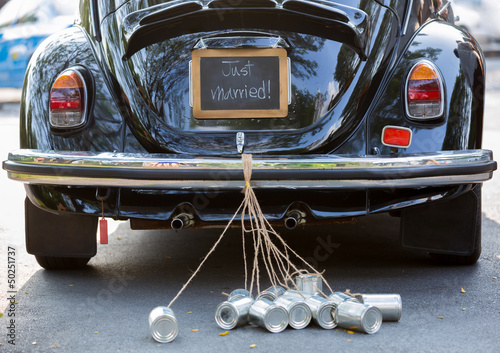 Rear view of a vintage car with just married sign and cans attac