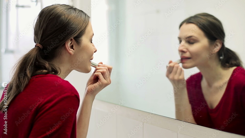 Young beautiful woman applying lipstick on her lips in bathroom Young beautiful woman applying lipstick on her lips in bathroom