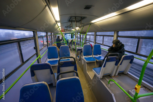 Interior of modern city bus with passengers in evening. Shot fro