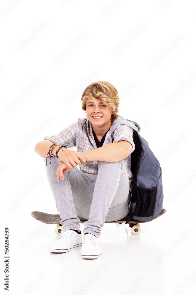 Fototapeta premium happy teen boy sitting on skateboard isolated