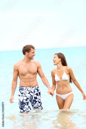 Couple on beach walking in water