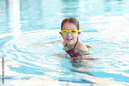 Schoolgirl with goggles in swimming pool