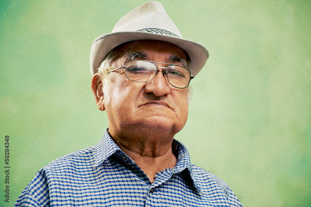 Portrait of serious old man with hat looking at camera