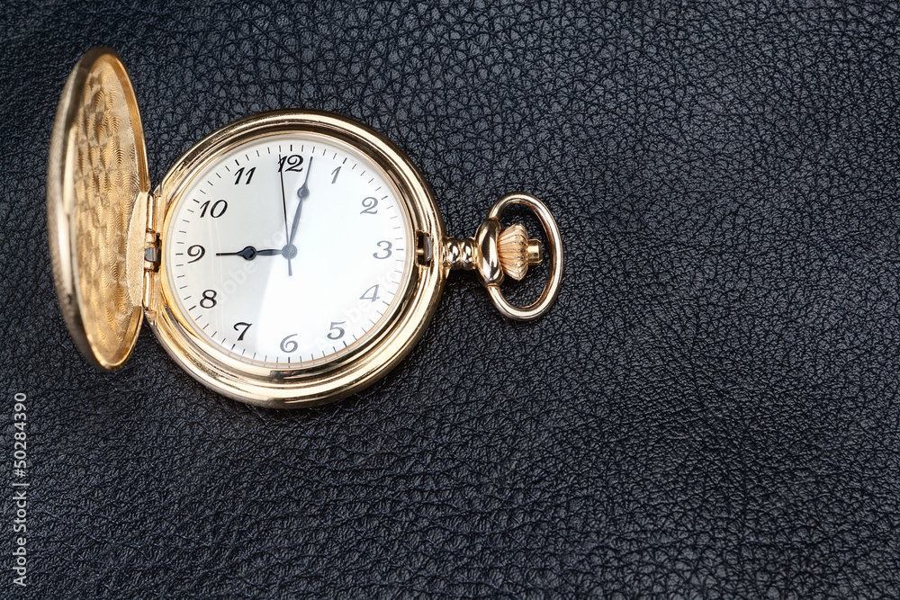 Antique gold pocket watch on a textured black leather. Close-up. Antique gold pocket watch on a textured black leather. Close-up.