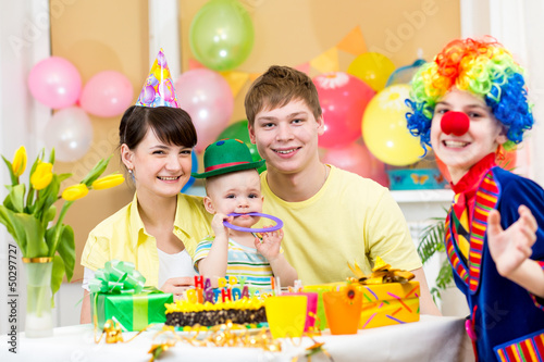 baby girl celebrating first birthday with parents and clown