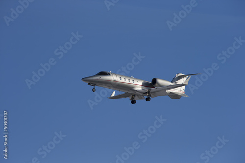 Business jet taking off isolated on a blue sky background.