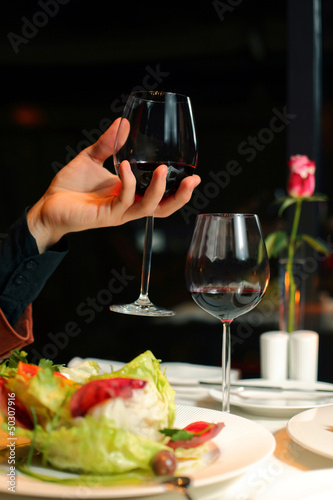 hand holds a glass of wine on a dark background