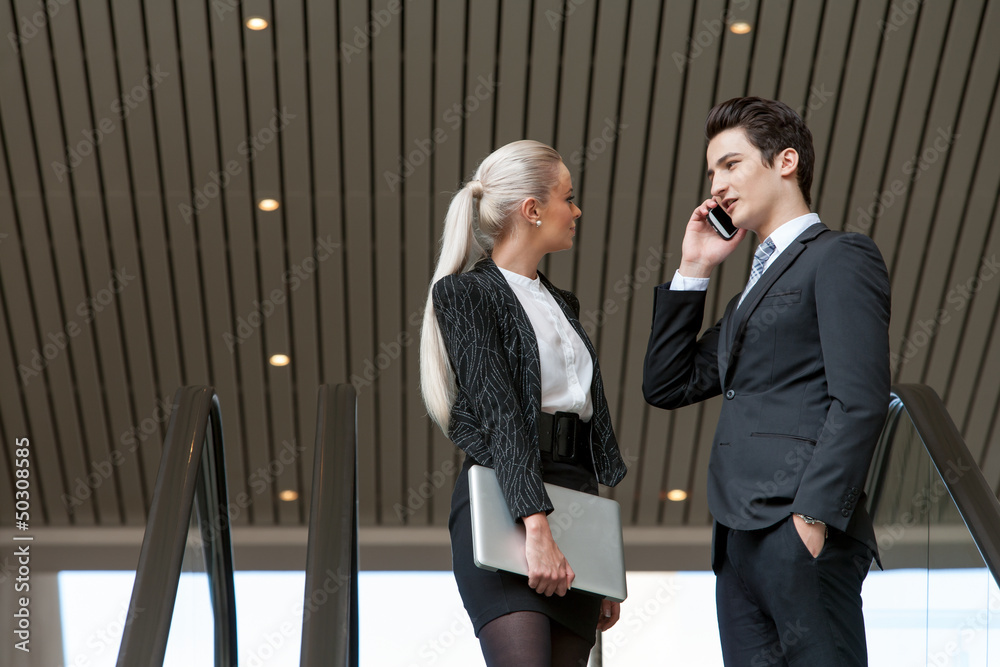 Business couple talking on phone in mall. Business couple talking on phone in mall.