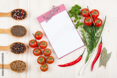 Recipe cook book, chili, cherry tomatoes, spices on white wood