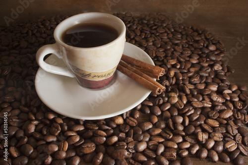 cup of coffee on a background coffee beans and brown wooden boar
