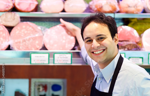 Shopkeeper showing mortadella in an italian grocery store photo