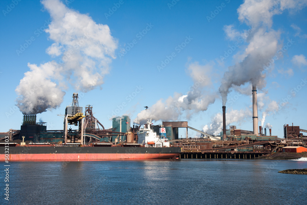 Big ship in front of a large steel factory in IJmuiden, Netherla