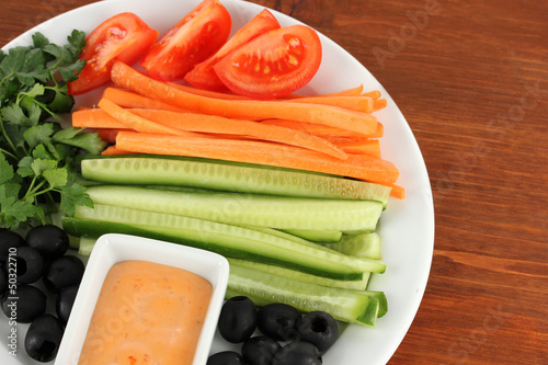 Assorted raw vegetables sticks in plate on wooden table close