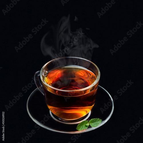 cup of black tea with mint and smoke on a black background