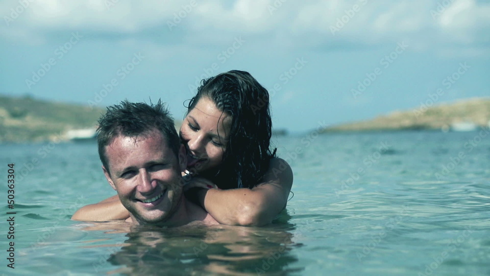 Happy couple standing in te sea and smiling, slow motion shot at Happy couple standing in te sea and smiling, slow motion shot at