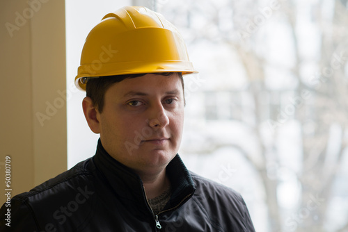 Worker in a helmet on a background window