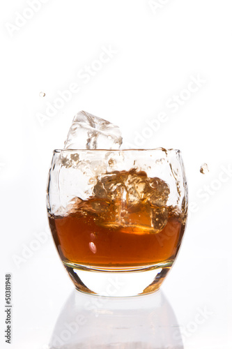 Ice cubes falling in a tumbler of whiskey