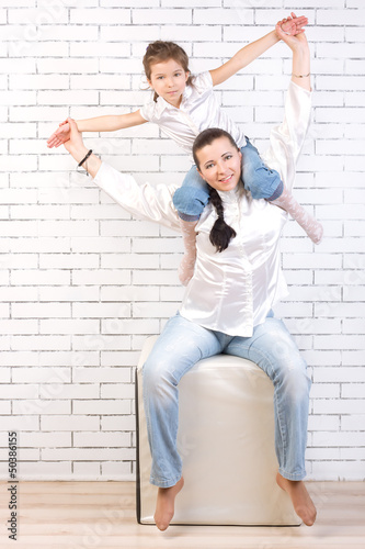 girl in jeans sitting on the neck of his mother