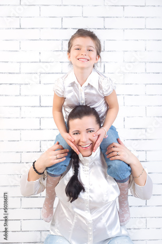 girl sitting on the neck of his mother