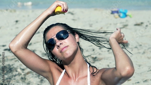 Beautiful girl sitting on the beach and squeeze lemon juice on h