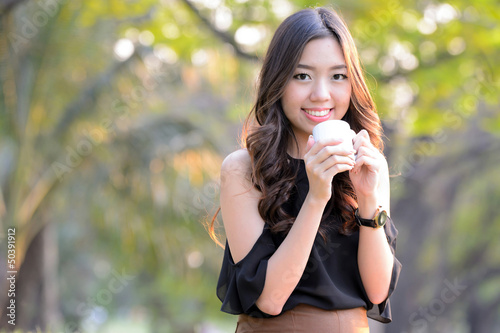 Asia woman drinking coffee in park outdoor.