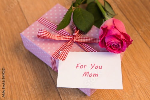 Pink wrapped present with mothers day card and pink rose