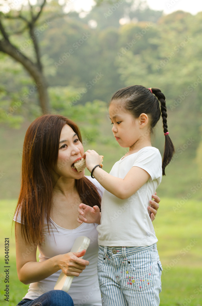 asian chinese girl feeding her mother in outdoor green park
