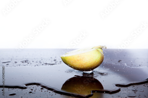 Apfel Hälfte in Wasserpfütze mit Wasserspritzern photo