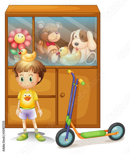 A young boy with his scooter and his toys in a cabinet