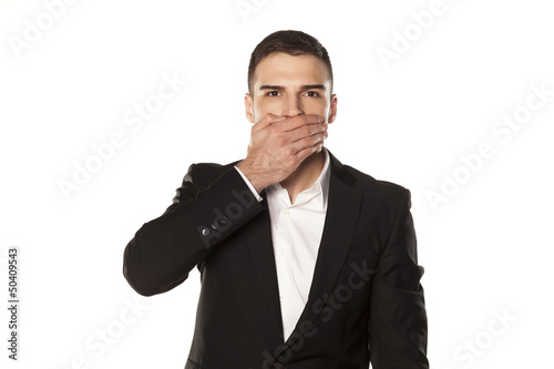 businessman in black suit, covering his mouth with his hand