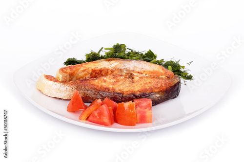 Salmon steak with vegetables on plate. Isolated on white