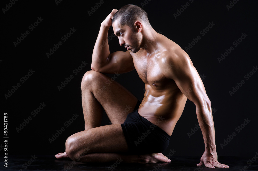Muscular man in dark studio Muscular man in dark studio