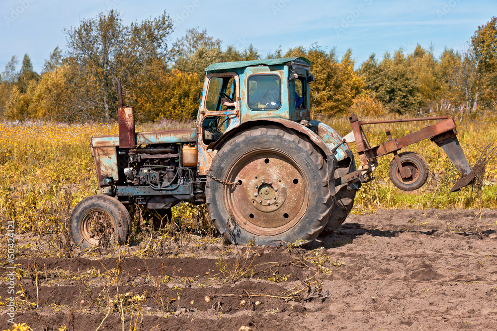 Old tractor at the field in sunny day Old tractor at the field in sunny day