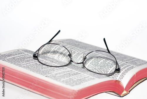 Selective focus of eye glasses on Bible